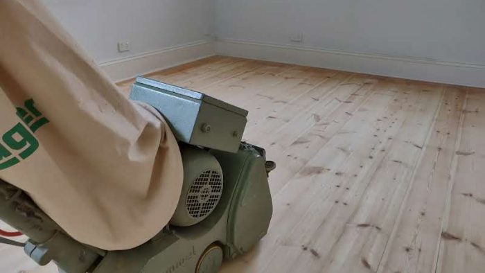 Professional floor sanding and polishing in progress.